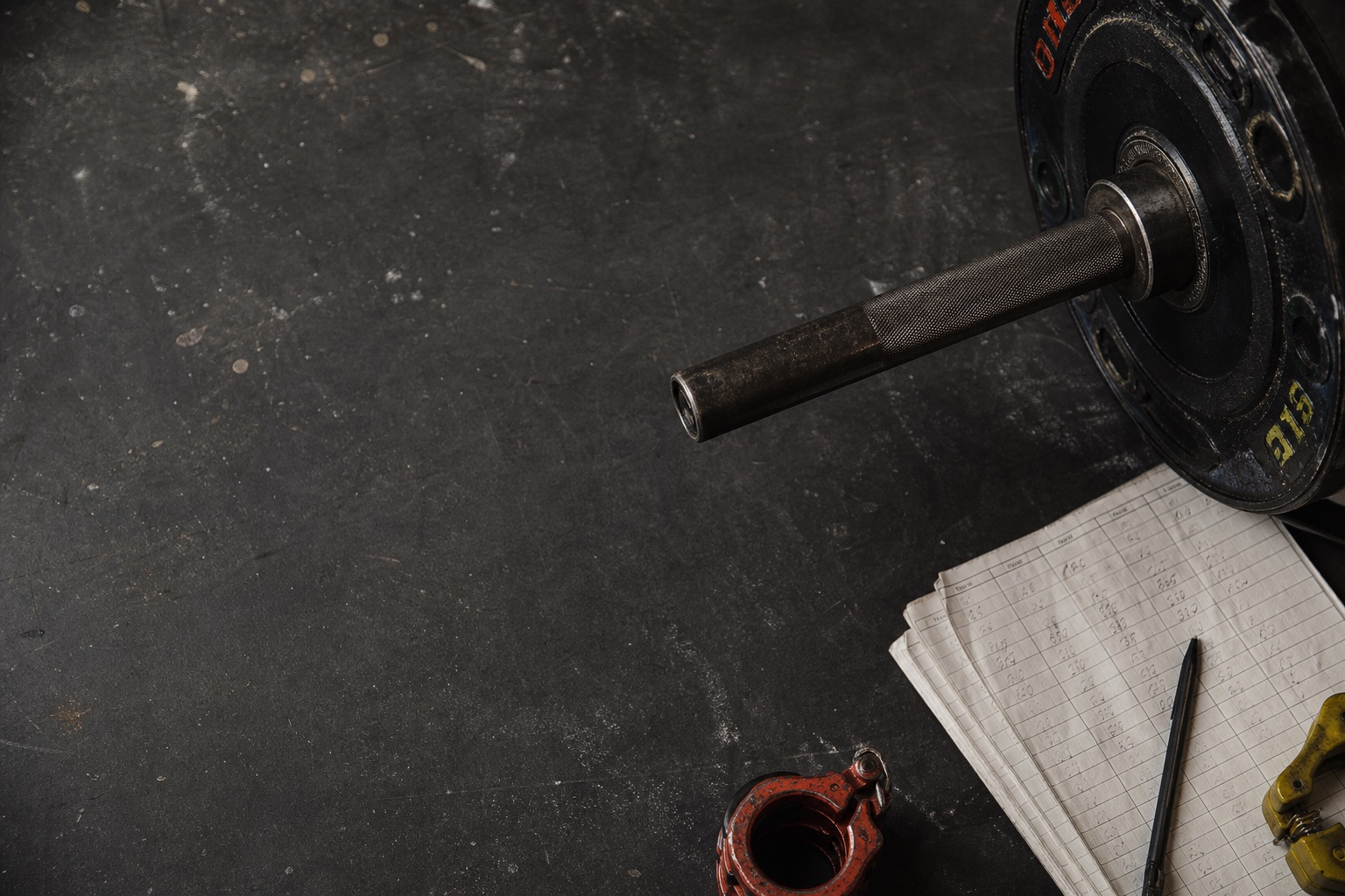 Barbell sleeve and training log on a gym floor